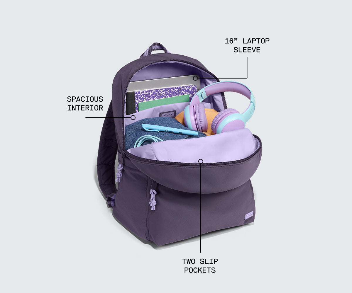 A purple backpack shown open on a light gray background with callout labels pointing to its features: spacious interior, 16-inch laptop sleeve, and two slip pockets. The bag is styled with sample items inside, including lavender headphones and a notebook.