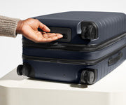 The Carry-On Flex suitcase in Navy Blue shown from below highlighting the underside grab handle