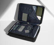 The Medium suitcase in Jet Black shown open on its side and packed with Away's packing organizers to show capacity and the interior compression system, designed to help you pack more in