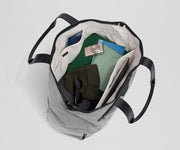 Top-down view of the tote packed with clothing, passport, headphones, a notebook, and a laptop among other travel essentials