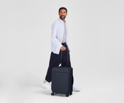 Person standing next to the Softside Bigger Carry-on for scale