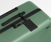 The Large suitcase in Sea Green shown shown from above highlighting TSA-approved combination lock and recycled leather luggage tag