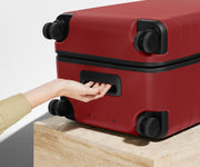 The Trunk suitcase in Tango Red shown from below highlighting the underside grab handle