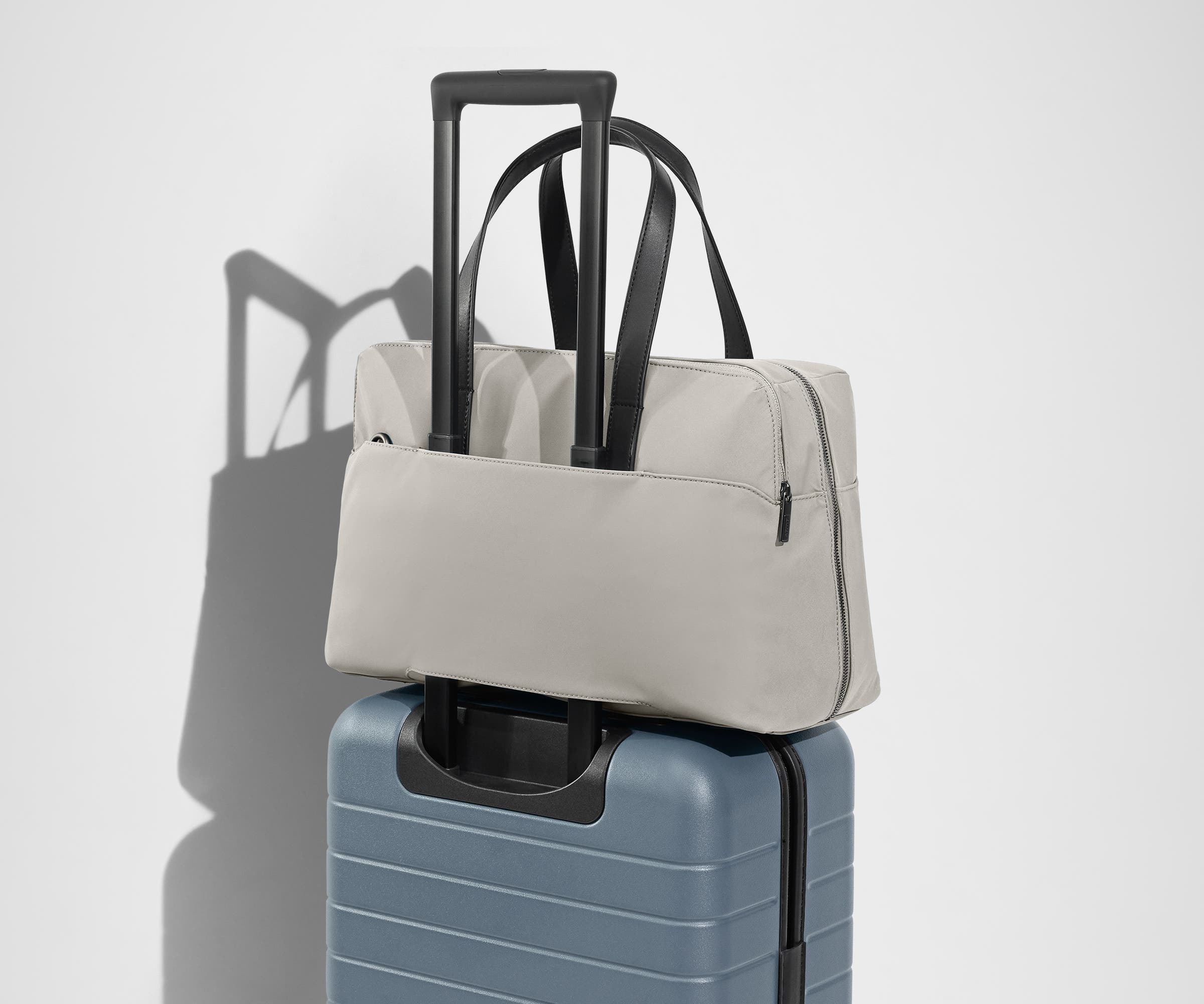 The Everywhere Bag secured to an Away suitcase by its trolley sleeve
