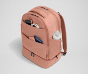 Exterior front pockets packed with travel essentials like a passport and phone, and the exterior bottle pocket packed with a milk bottle