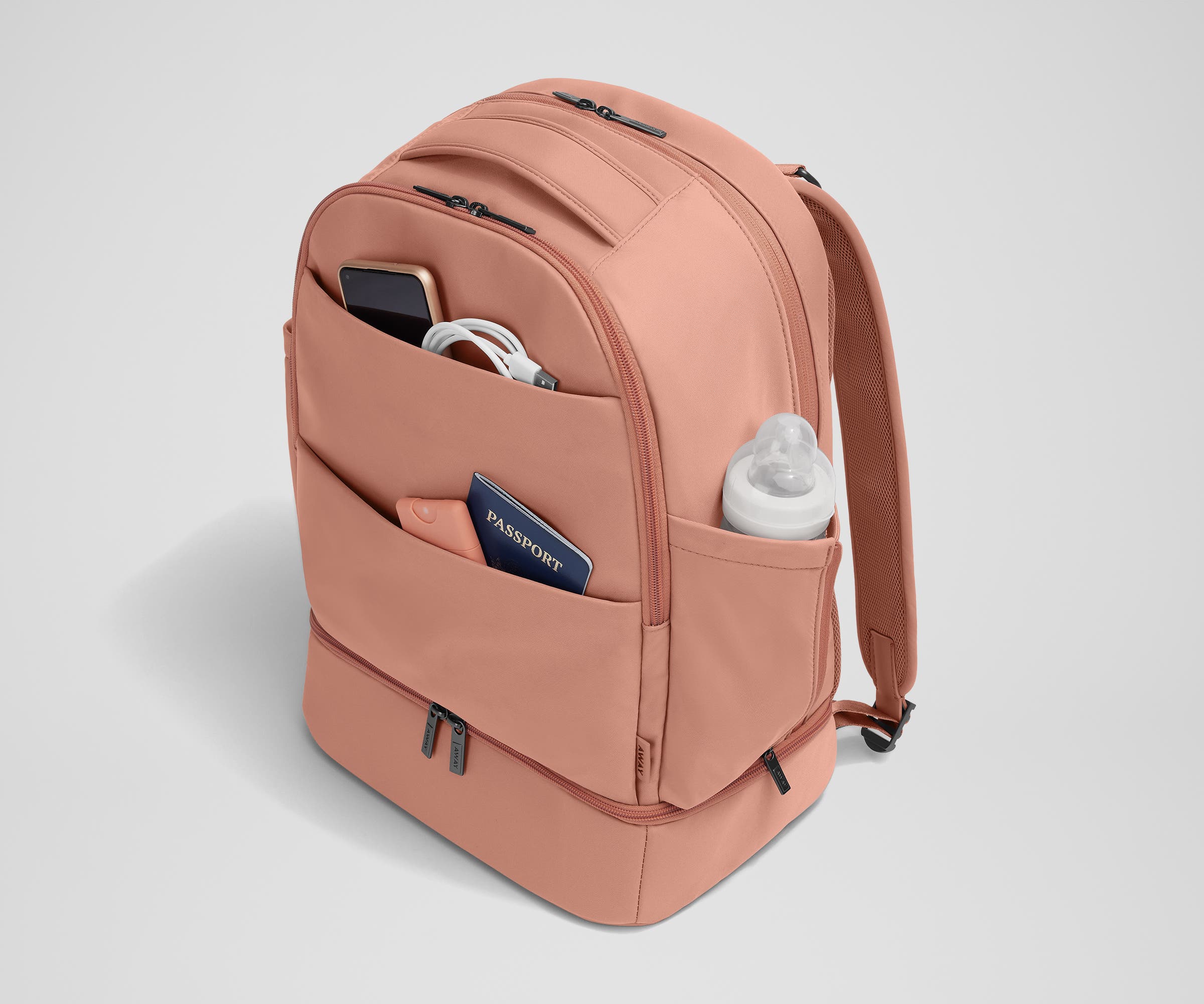 Exterior front pockets packed with travel essentials like a passport and phone, and the exterior bottle pocket packed with a milk bottle