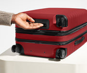 The Bigger Carry-On Flex suitcase in Tango Red shown from below highlighting the underside grab handle