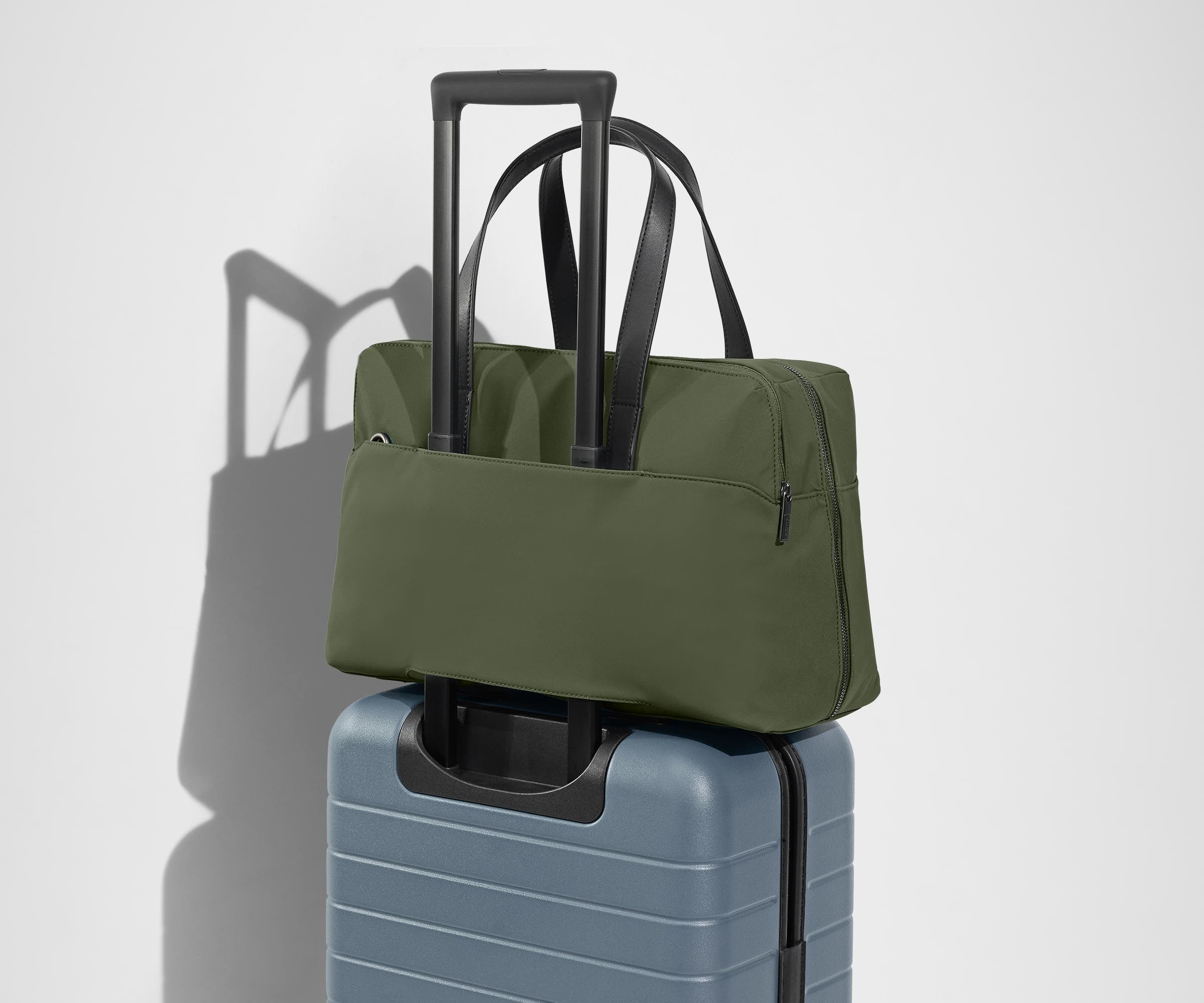 The Everywhere Bag secured to an Away suitcase by its trolley sleeve