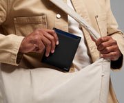 Person packing the Passport Wallet in the Featherlight Crossbody bag