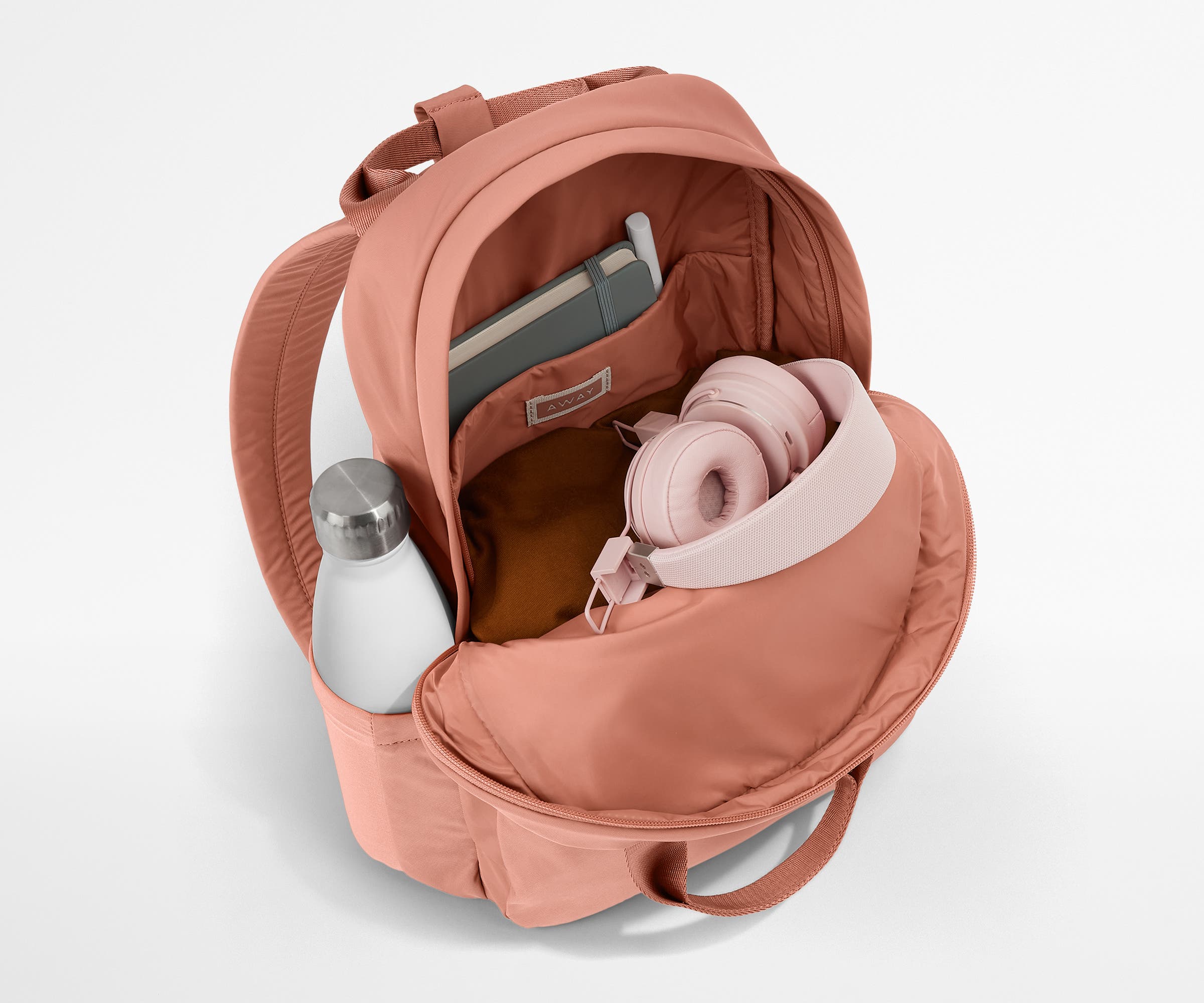 Featherlight Backpack packed with a sweater, notebook, headphones, and water bottle