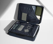 The Large suitcase in Navy Blue shown open on its side and packed with Away's packing organizers to show capacity and the interior compression system, designed to help you pack more in