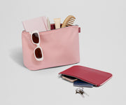 Pouch duo packed with travel essentials like a notebook, passport, keys, and sunglasses