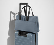 The Everywhere Bag secured to an Away suitcase by its trolley sleeve