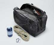 Active Duffle 55L packed with travel essentials and outdoor gear including a packing cube, sunglasses, wallet, carabiner and rope, and water bottle