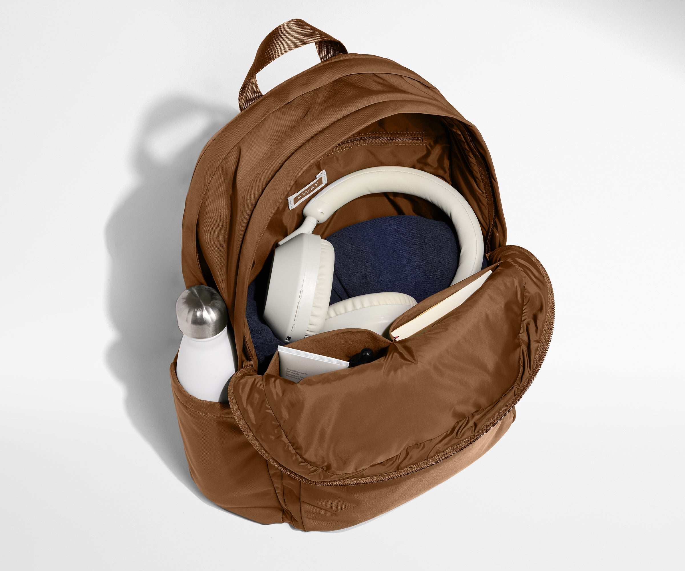 Front compartment packed with a notebooks, headphones, and clothing