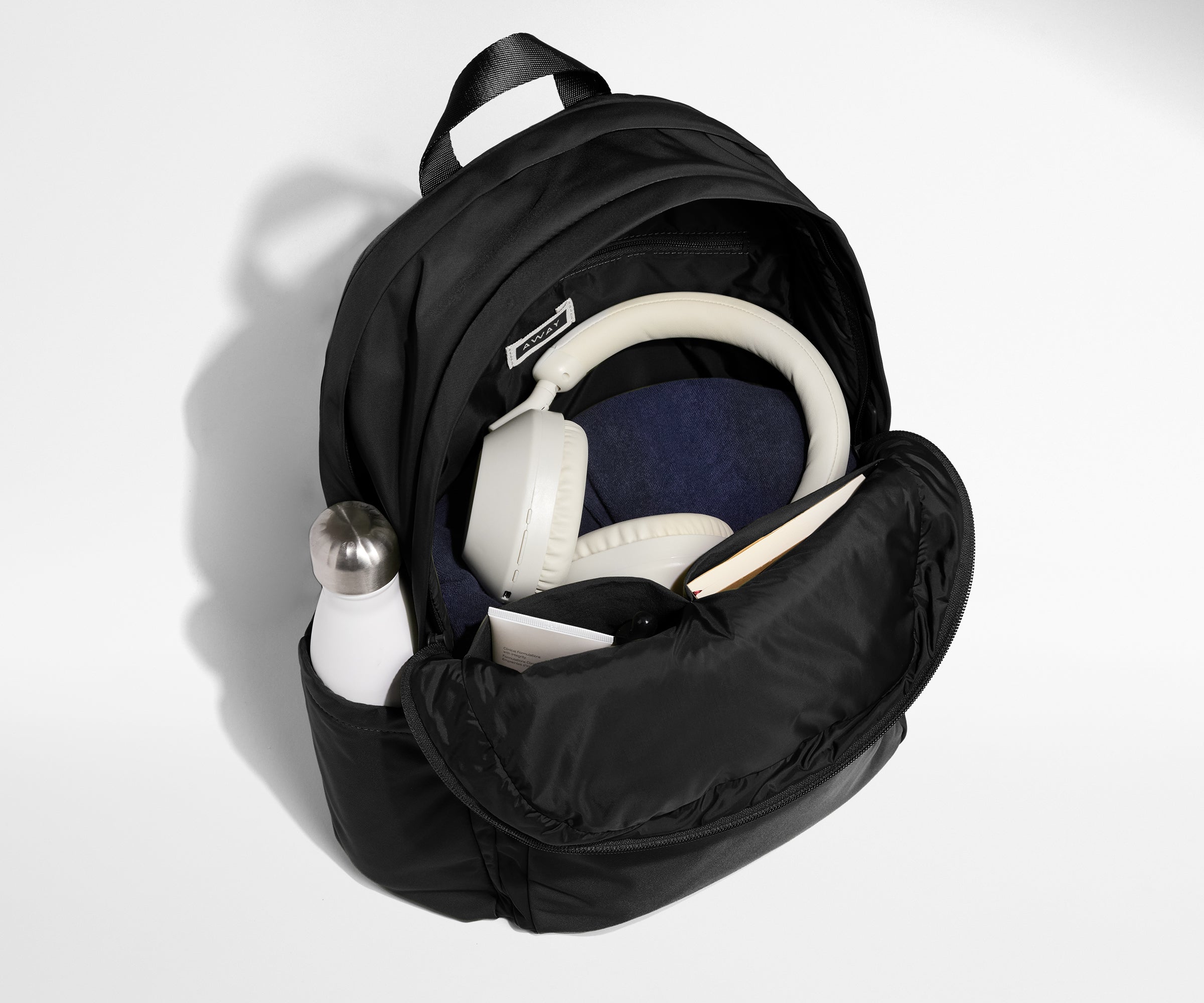 Front compartment packed with a notebooks, headphones, and clothing