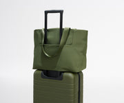 Green tote bag on top of a green suitcase against a white background