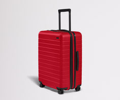 Red suitcase with black handle and wheels on a light gray background