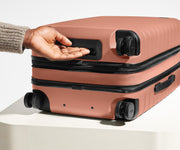The Bigger Carry-On Flex suitcase in Clay Pink shown from below highlighting the underside grab handle