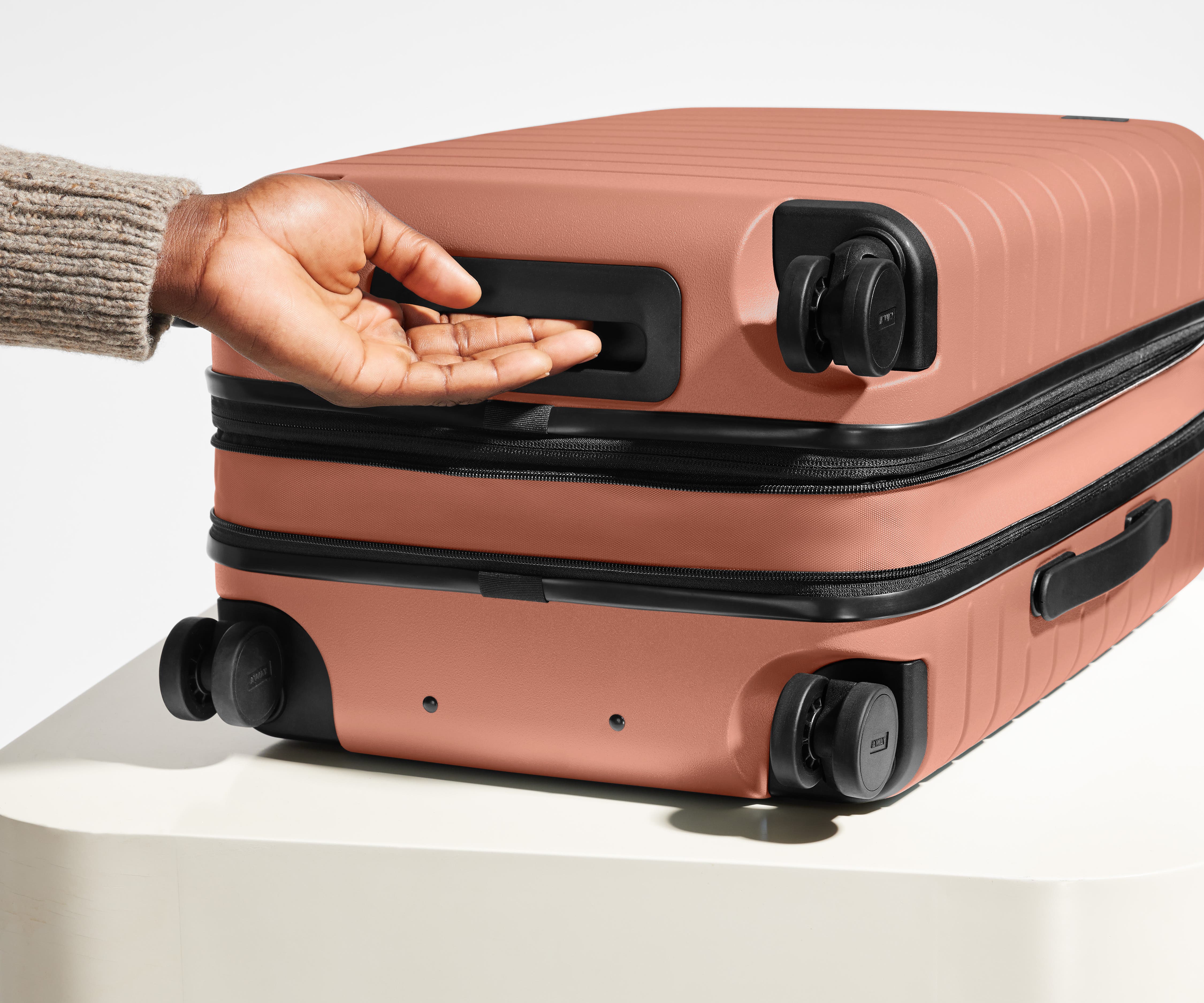 The Bigger Carry-On Flex suitcase in Clay Pink shown from below highlighting the underside grab handle