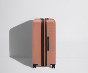 Side product view of The Large Flex suitcase in Clay Pink shown fully expanded