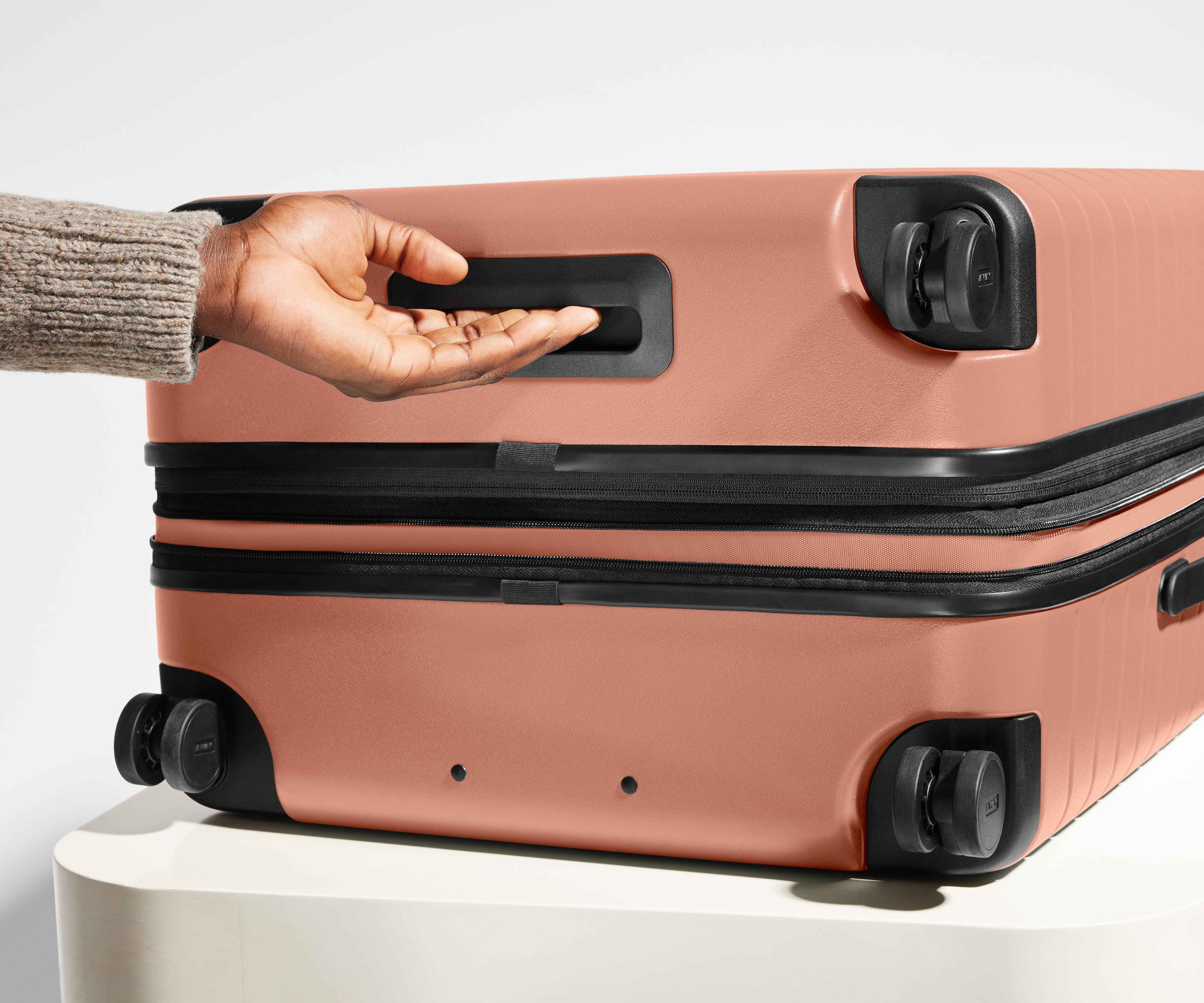 The Medium Flex suitcase in Clay Pink shown from below highlighting the underside grab handle