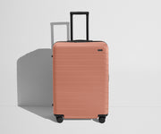 Front product view of The Medium Flex suitcase in Clay Pink with raised handle