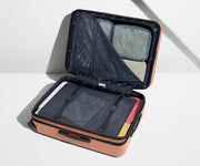 The Medium Flex suitcase in Clay Pink shown open on its side and packed with Away's packing organizers to show capacity and the interior compression system, designed to help you pack more in