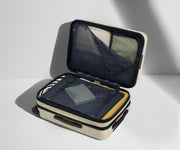 The Bigger Carry-On Flex suitcase in Salt White (Gloss) shown open on its side and packed with Away's packing organizers to show capacity and the interior compression system, designed to help you pack more in