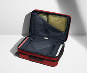 The Bigger Carry-On Flex suitcase in Tango Red shown open on its side and packed with Away's packing organizers to show capacity and the interior compression system, designed to help you pack more in