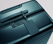 Teal suitcase with a luggage tag on a light gray background