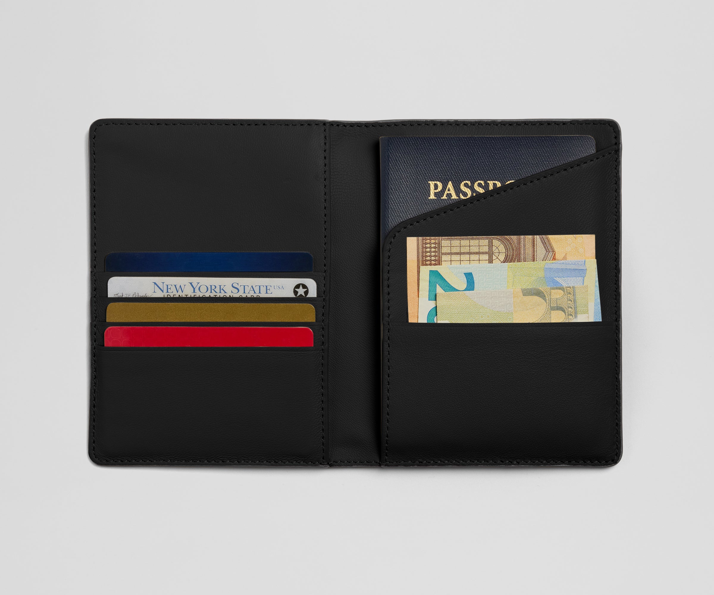 Black leather passport holder with various cards and a passport on a light gray background
