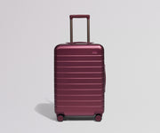 Maroon suitcase with a handle on a light gray background
