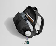 Daypack packed with a light jacket, sunglasses, notebook, map, and other travel gear. Water bottle featured in the exterior water bottle pocket.