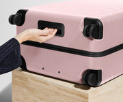 The Large suitcase in Blush Pink shown from below highlighting the underside grab handle