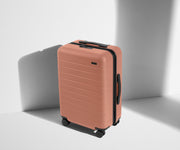 Angled product view of The Bigger Carry-On suitcase in Clay Pink