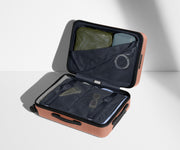 The Bigger Carry-On suitcase in Clay Pink shown open on its side and packed with Away's packing organizers to show capacity and the interior compression system, designed to help you pack more in