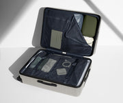 The Large suitcase in Cloud Gray shown open on its side and packed with Away's packing organizers to show capacity and the interior compression system, designed to help you pack more in