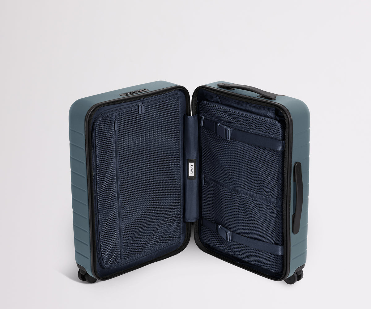 The Carry-On suitcase in Coast Blue shown open in an upright position to show interior organization and compression system