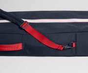 Navy bag with red strap and zipper on a light gray background