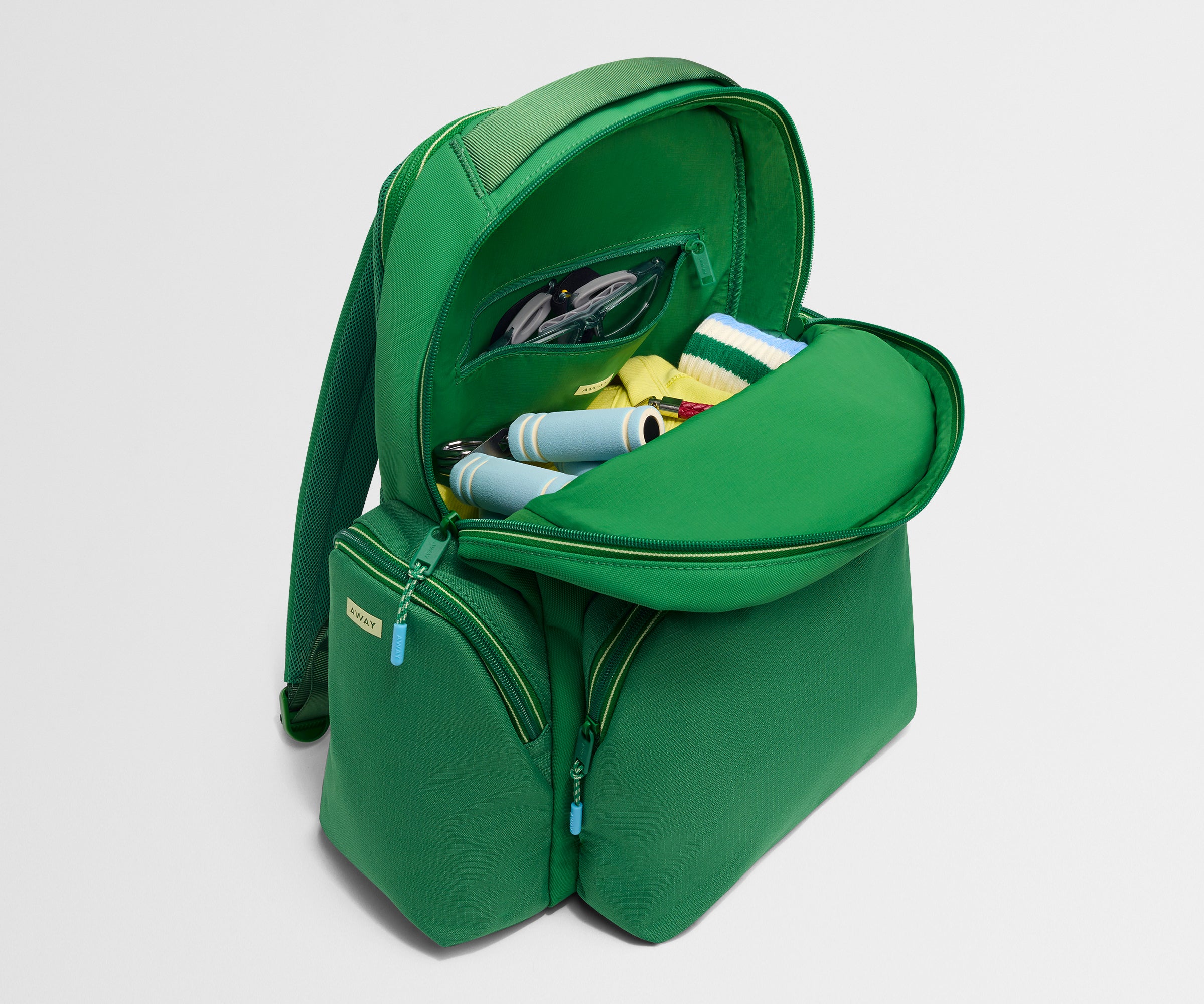Green backpack with items inside on a light gray background