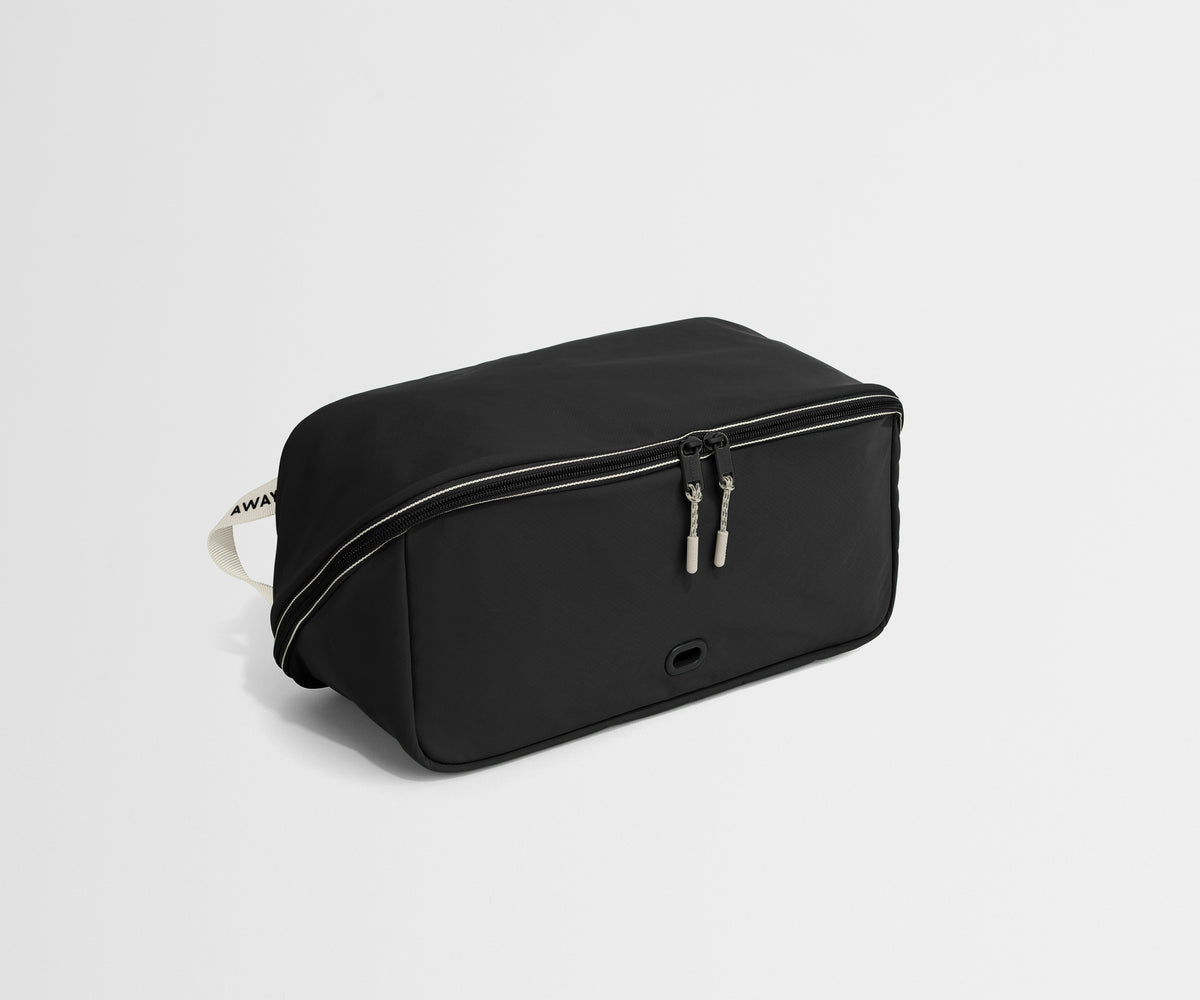 Black shoe bag with a strap on a light gray background