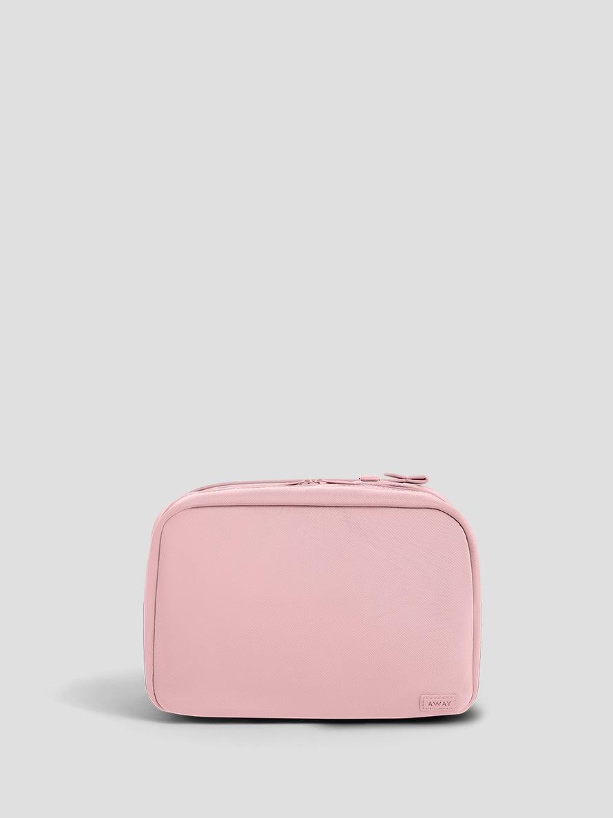 A light pink zippered toiletry bag with rounded corners, shown from the front against a solid light gray background.