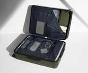 The Large suitcase in Olive Green shown open on its side and packed with Away's packing organizers to show capacity and the interior compression system, designed to help you pack more in