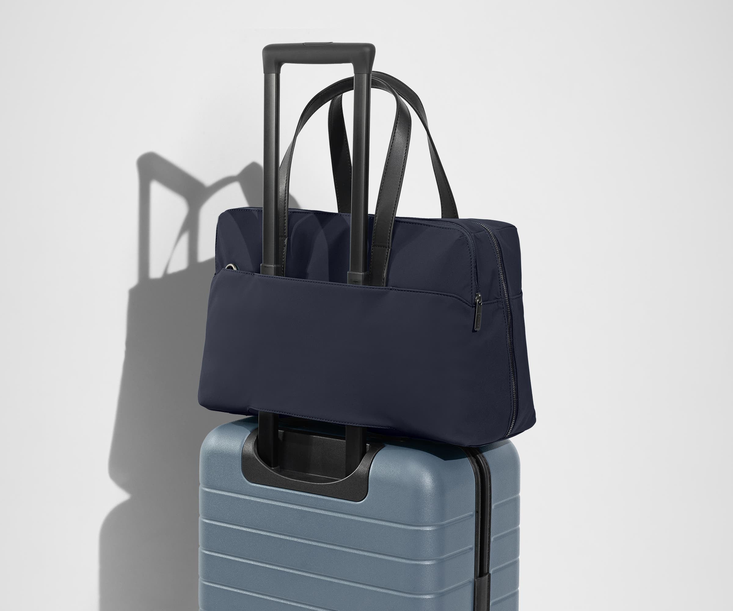 The Everywhere Bag secured to an Away suitcase by its trolley sleeve