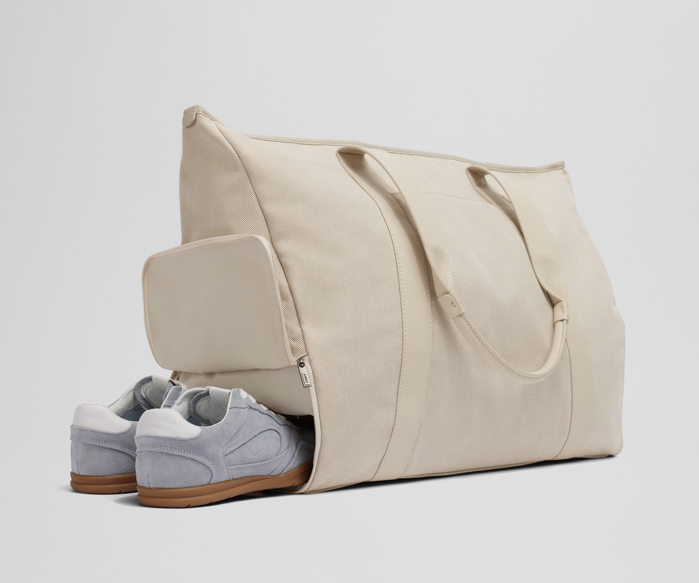 A pair of sneakers in the zippered shoe compartment