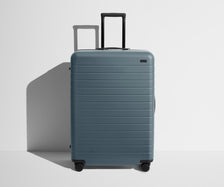 Front product view of The Large suitcase in Coast Blue with raised handle