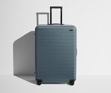 Front product view of The Large suitcase in Coast Blue with raised handle