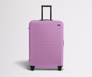 Front product view of The Large suitcase in Taffy Purple with raised handle