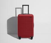 Front product view of The Bigger Carry-On Flex suitcase in Tango Red with raised handle